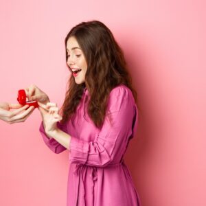 Portrait of surprised girlfriend receive marriage proposal, looking at hand with engagement ring and